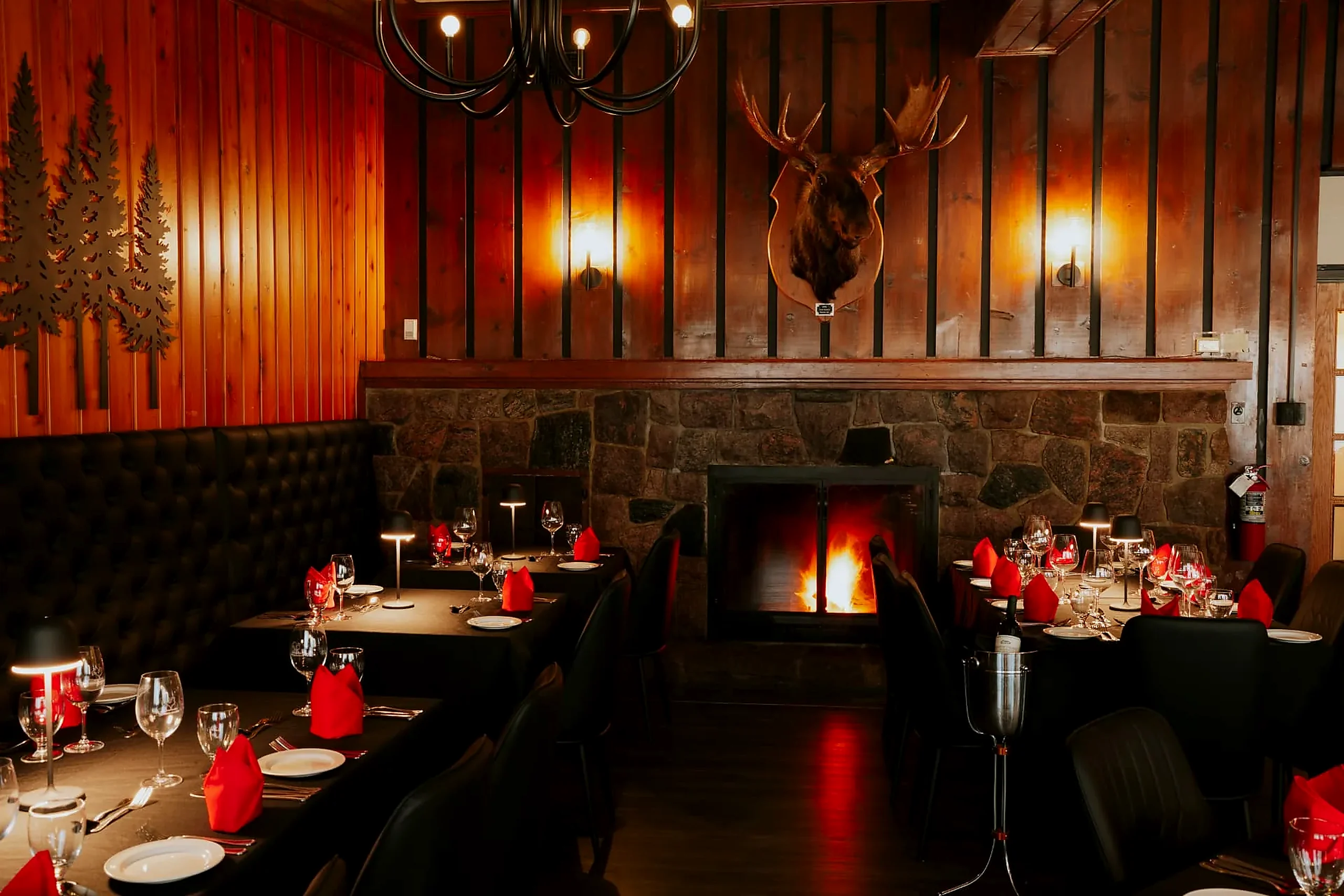 Dinner by the fire The Grenfell Restaurant dining room with the stone fireplace lit and tables set with red napkins