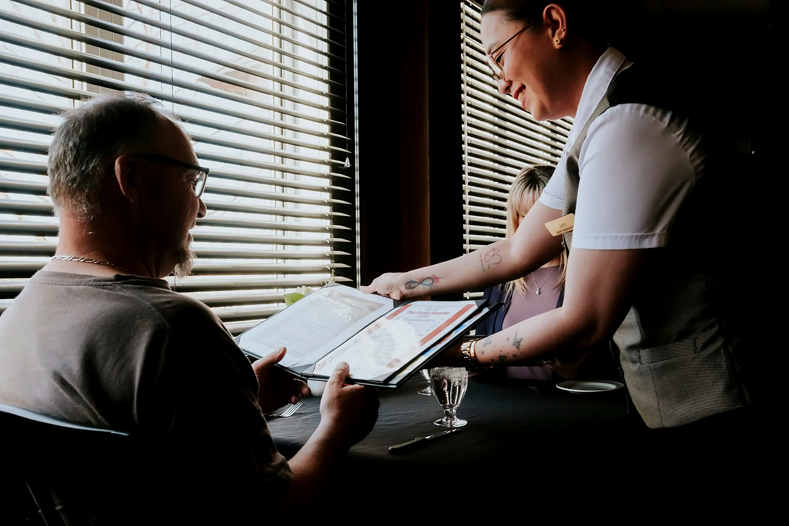 Table service, window seat A server presenting the menu to guests at a window table in the restaurant