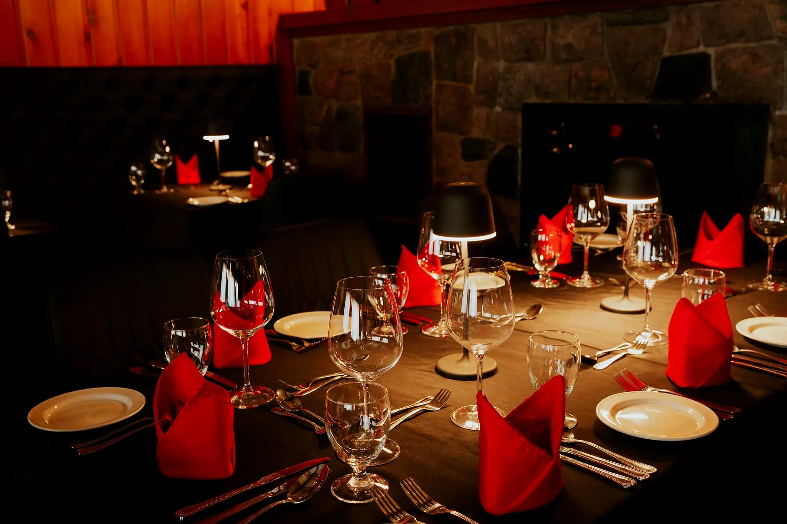 Set for two Table for two set with red napkins and wine glasses beside the stone fireplace